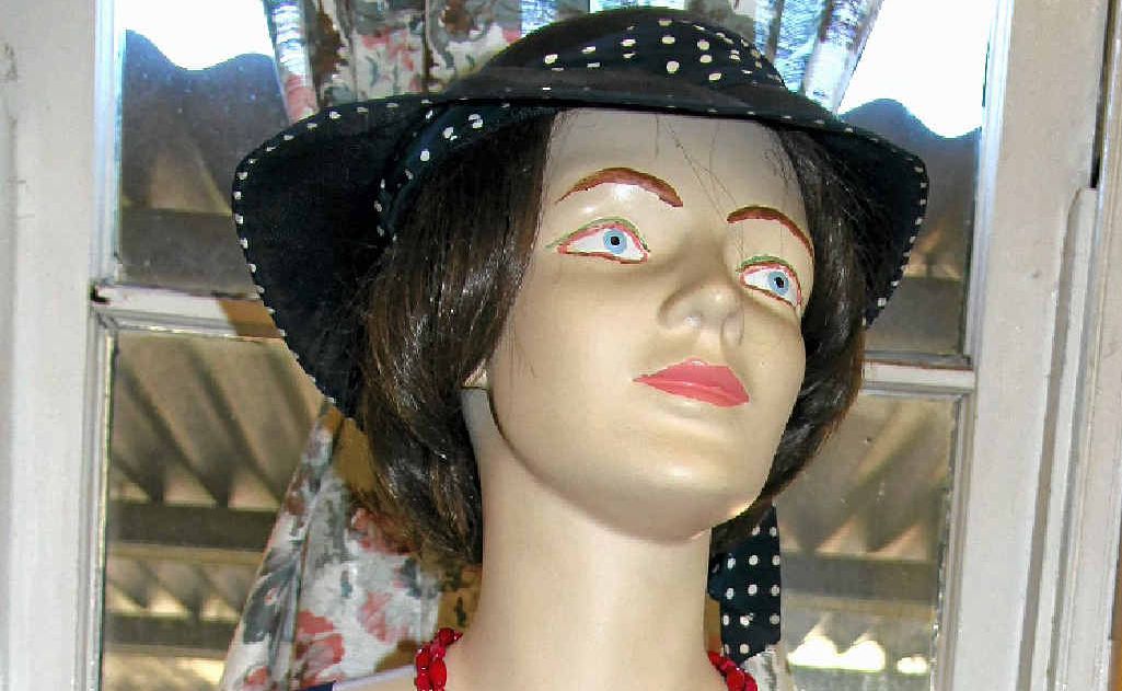 A spotted blue dress topped off with beads and a hat.